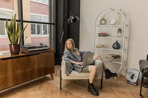 A woman sitting on the chair holding a MacBook