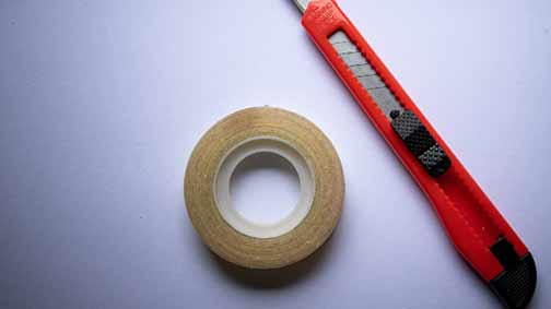 A yellow roll tape and a cutting tool on a blue surface.
