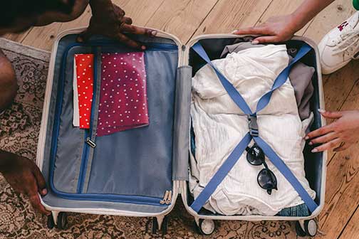 A photo of an open suitcase with clothes and sunglasses