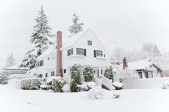 A white house covered in snow with its chimney visible