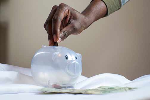 Person putting coin into a piggy bank.