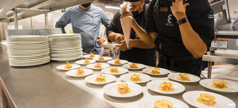 Cooks setting plates in a commercial kitchen.