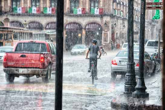 A man riding his bike in heavy rain.