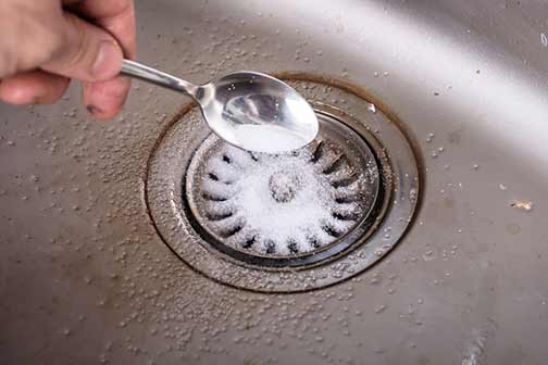a person using baking soda for drain smell