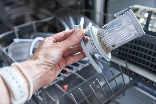 a woman holding her dirty dishwasher filter