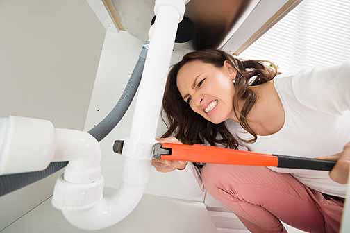 a woman attempting DIY plumbing repairs