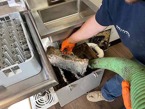 a grease trap being cleaned in a commercial kitchen.