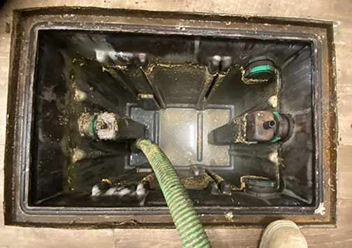 a restaurant kitchen grease trap being cleaned out and maintained properly.