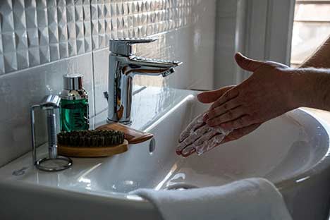 a woman washing her hands in a sink.