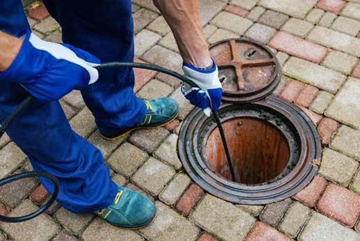 a commercial plumber using hydro jetting technology to clean a business drain.