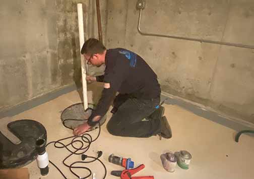 a plumber installing a sewage ejector pump in a newly built home.