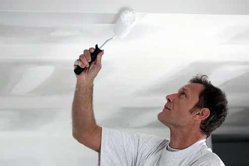 a man painting a ceiling.