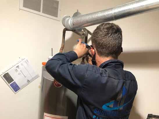 a professional plumber repairing a water heater.