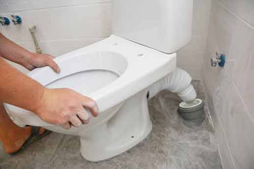 a plumber installing toilet that will help reduce water usage.