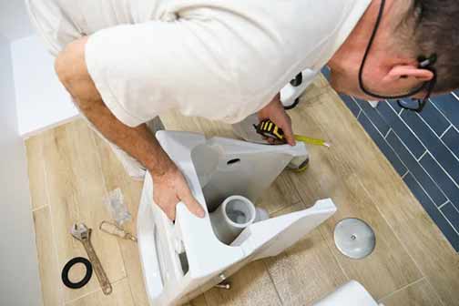 a man replacing a flange on his toilet.