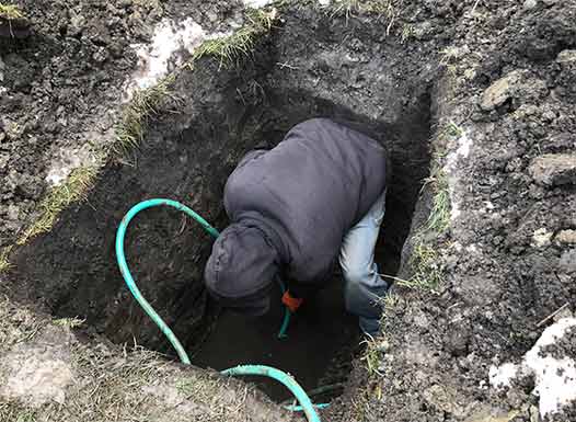 a plumber performing sewer line repairs in winter.