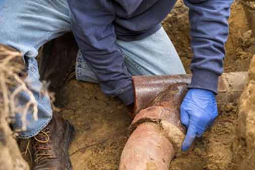 a man repairing a broken sewer pipe.