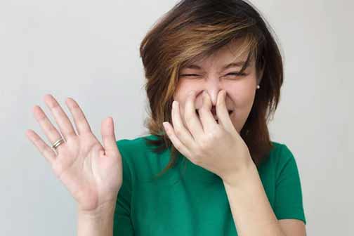 a woman smelling bad sewer odors from her drain.