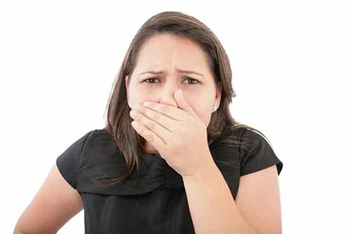 a woman smelling unpleasant odors in her home.