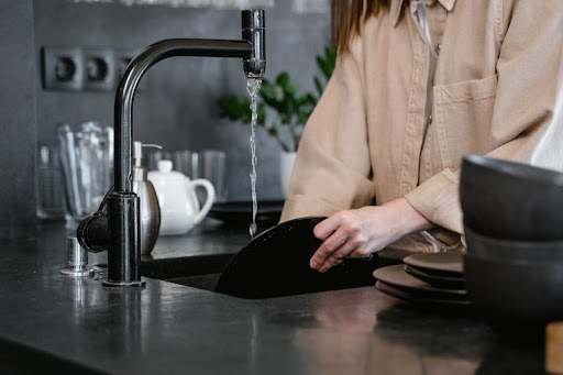 a woman washing dishes in sink.