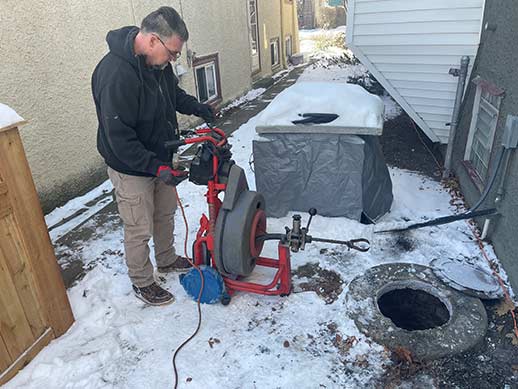 a plumber performing a winter sewer rodding.